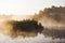 Dark grassy foggy polish lake with island in the middle