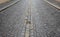 Dark gray basalt tiles. A very old road with edges and a center line formed by a light stone, probably quartz or gneiss