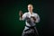 On a dark green background, an adult athlete does formal karate exercises