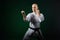 On a dark green background, an adult athlete trains formal karate exercises