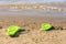 Dark green flip flops lie on bank of the river