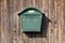 Dark green metal vintage retro mailbox with lock mounted on wooden boards barn wall