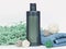 Dark green unbranded hygienic product bottle with rattan balls, towel and shredded paper on white background. Blank label with gra