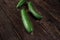 Dark green whole raw cucumbers on old rustic wooden table