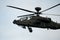 Dark grey army attack helicopter in flight during the daytime
