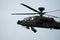 Dark grey army attack helicopter in flight during the daytime