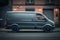 Dark grey cargo van. City street background. Side view