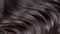 Dark hair background showcases smooth, shiny, and healthy hair texture beautifully