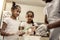 Dark-haired daughters with faces in flour helping father in kitchen