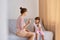 Dark haired female with hair bun speech pathologist having lesson with little girl, training pronunciation of sounds and