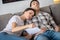 Dark-haired female holding paper, resting her head on brunette male shoulder