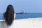 Dark haired female person observing floating military ship, focus on background