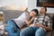 Dark-haired female resting her head on brunette male shoulder, both resting on sofa