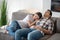 Dark-haired female resting her head on brunette male shoulder, both resting on sofa