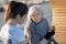 Dark-haired kind volunteer supporting aged homeless woman