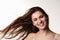Dark haired, late teen girl, hair blowing, smiles to camera