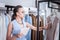 Dark-haired owner of shop holding tablet while checking price tags of dresses