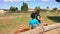 Dark-haired woman is leading a pony with a boy outdoors at the sunny summer day