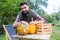 A dark-haired young farmer with pumpkins looking contented