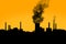 Dark harmful smoke from chimneys of power plant silhouette on sunset clear orange sky