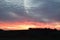 dark hills with bold forest and orange burning clouds at dawn