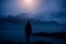 Dark human silhouette in a thick fog against the background of forest, hills and mountain river. Mysterious female figure on