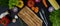 Dark kitchen table with assorted fresh vegetables, chopping board and silverware