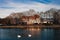 Dark landscape photo of Piestany city in Slovakia with swans on the blue river and hotel on background on sunset.  Castle on