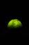 Dark low key image of a fresh and ripe green lime fruit lit from above only