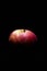 Dark low key image of a fresh and ripe red apple lit from above only