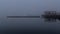 Dark moody pier in fog in the evening