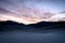 Dark Mountains Loom Behind Sand Dunes