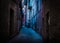 A dark and narrow, back alley painted with blue and magenta light taken in Recanati, Macerata, Italy