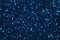 Dark navy blue sparkling background from big foil turquoise sequins, closeup. Texture backdrop with shiny crumb pattern
