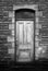 Dark old faded wooden house door with stone wall