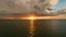 Dark ominous thunderstorm clouds forming on overcast sky during heavy rainfall season over ocean surface at sunset