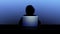 Dark person with hood silhouetted against open laptop