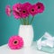 Dark pink gerberas in a vase on a table with beautiful present. Happy Mother`s Day, Women`s Day, Valentine`s Day or Birthday.