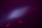 On a dark purple fine-grained background, a light purple cloud of light and a red laser beam