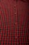 Dark red checkboard pattern shirt fabric background, garment texture with buttons, vertical shot