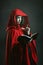 Dark red hooded witch reading a book