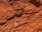 Dark red orange brown rock texture with cracks. Close-up. Rough mountain surface.