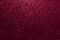 Dark red sparkling background from small sequins, closeup. Brilliant backdrop