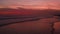 Dark red twilight on ocean shore. Crimson waves rolling on sand beach. Sunset on seaside. Sea water washing coast