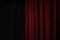 Dark red velvet curtain on one side of a black theatre stage, event background concept with large copy space