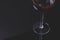 Dark red wine on a wineglass on a dark black background