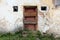 Dark red wooden doors with boards nailed across on abandoned dilapidated brick house