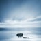 Dark rocks in a blue ocean under cloudy sky in a bad weather.