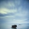 Dark rocks in a blue ocean under cloudy sky in a bad weather.