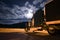 Dark semi truck reefer in night light with moony clouds